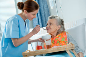 Certified nursing assistant helping an elderly patient.