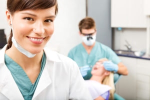 Dental Assistant with a patient and dentist in exam room.